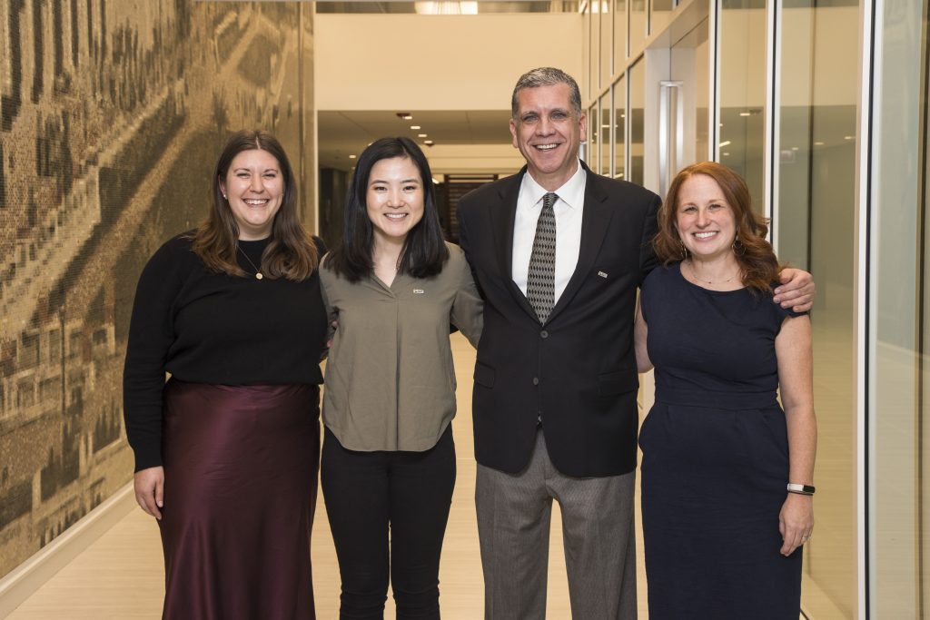 DRA's Emily Roznowski, future DRA staff Raika Kim, DRA Board member Barry Taylor, and DRA's Rachel Weisberg posing and smiling in an office hallway.