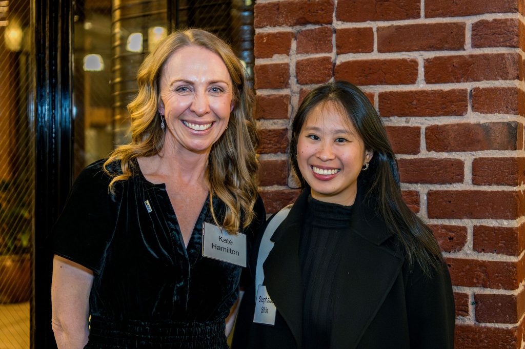 DRA's Kate Hamilton posing and smiling with a guest in front of a brick wall.