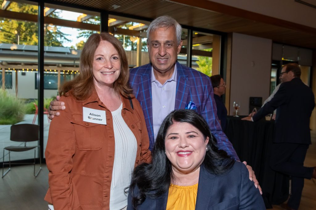 DRA's Rebecca Williford and Honoree Neel Chatterjee smiling and posing with an event guest